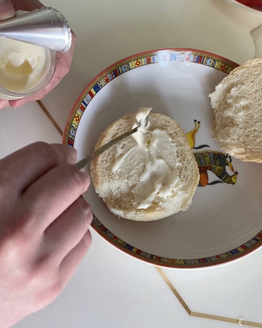 Gros plan dune cuillère étalant de la sauce crémeuse sur la mie dun pain à burger moelleux.