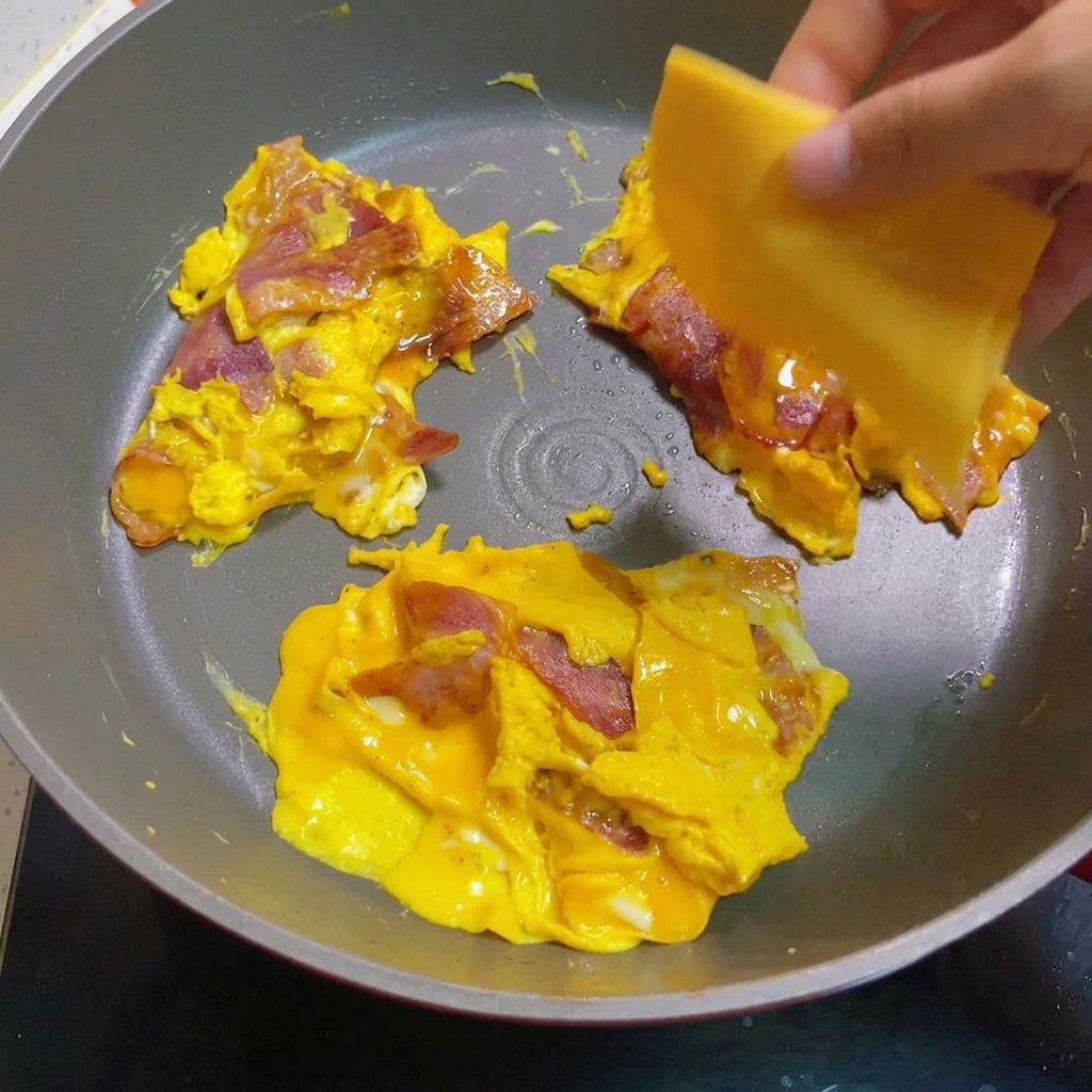 Œufs brouillés et bacon recouverts de fromage fondu.