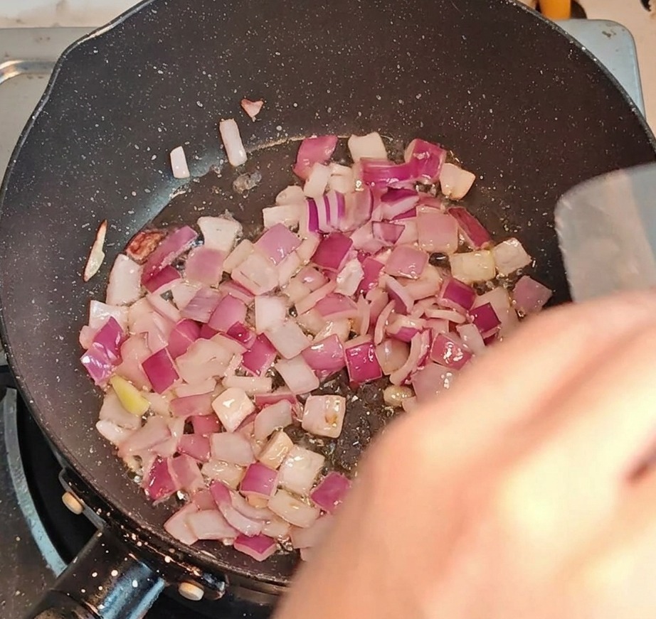 Bacon haché et oignons sautés ensemble dans une poêle à feu vif.