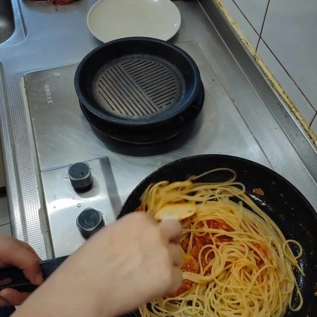 Pâtes mélangées dans une riche sauce tomate dans la poêle, avec de la vapeur montant lors de lémulsion.