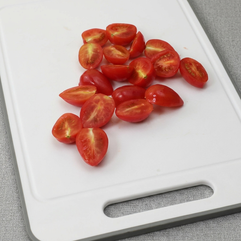 Tomates cerises coupées en deux sur une planche à découper.