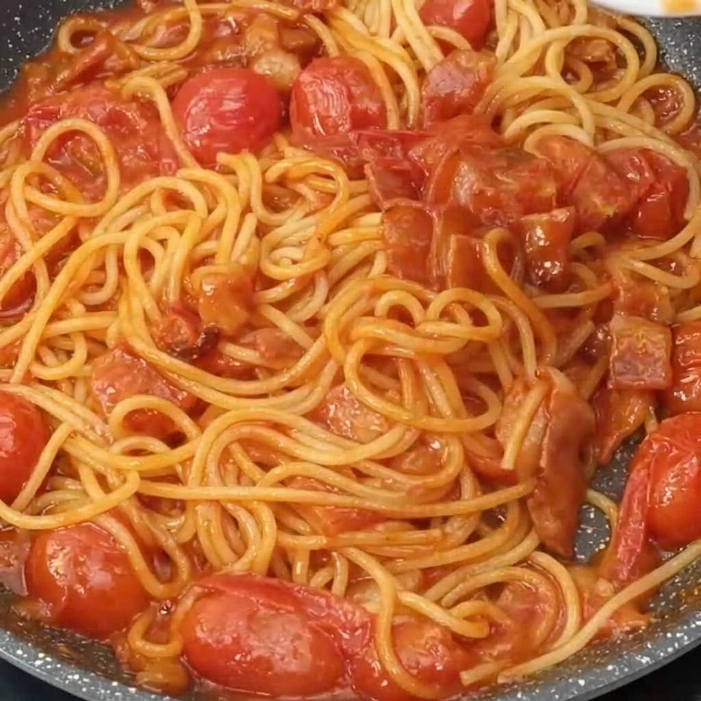 Spaghettis dans la poêle parsemés de parmesan râpé.