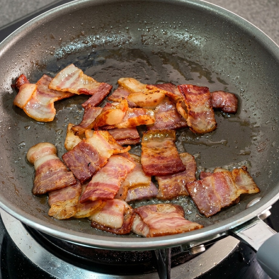 Gras de bacon fondu et morceaux dorés dans la poêle.