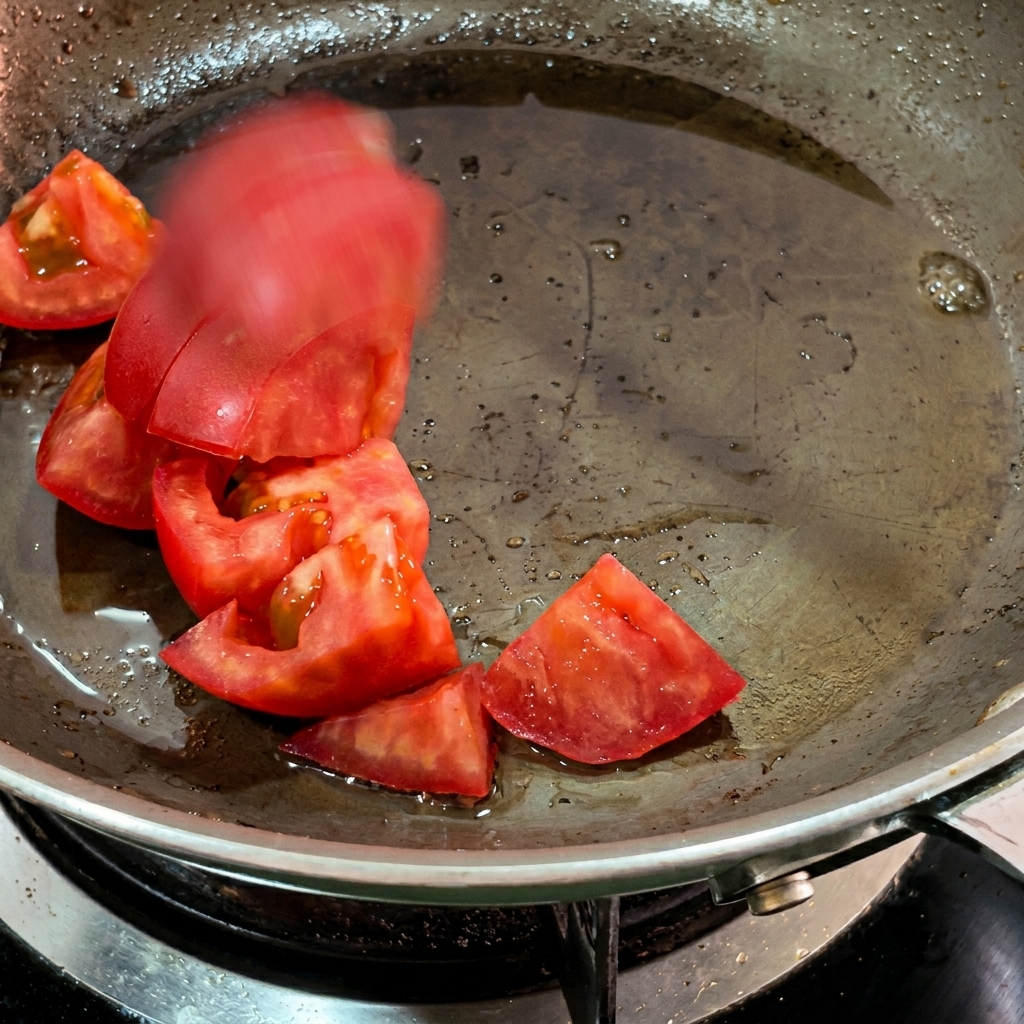 Morceaux de tomates qui ramollissent dans le gras de bacon.