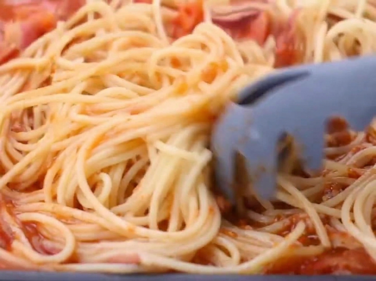 Spaghettis cuits ajoutés à la sauce tomate et bacon.