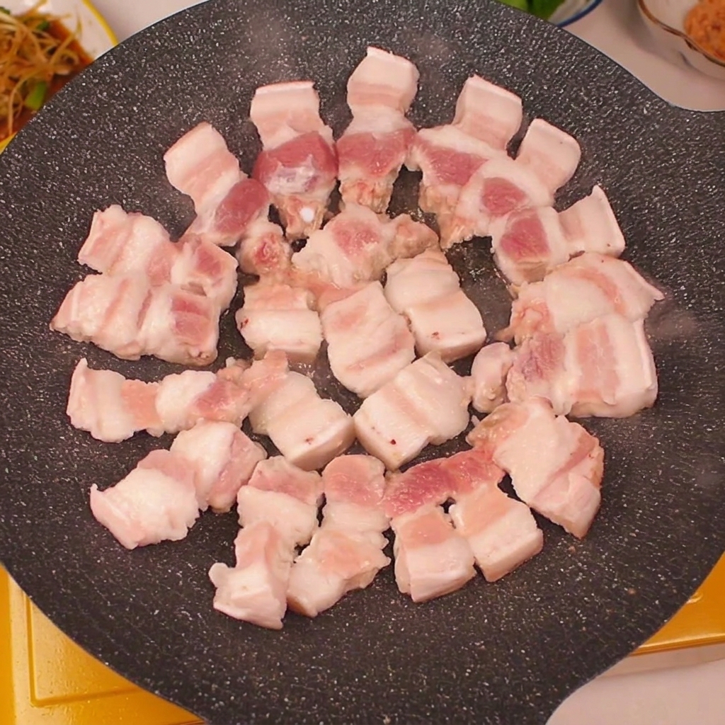Tranches de poitrine de porc disposées en cercle dans une poêle chaude.