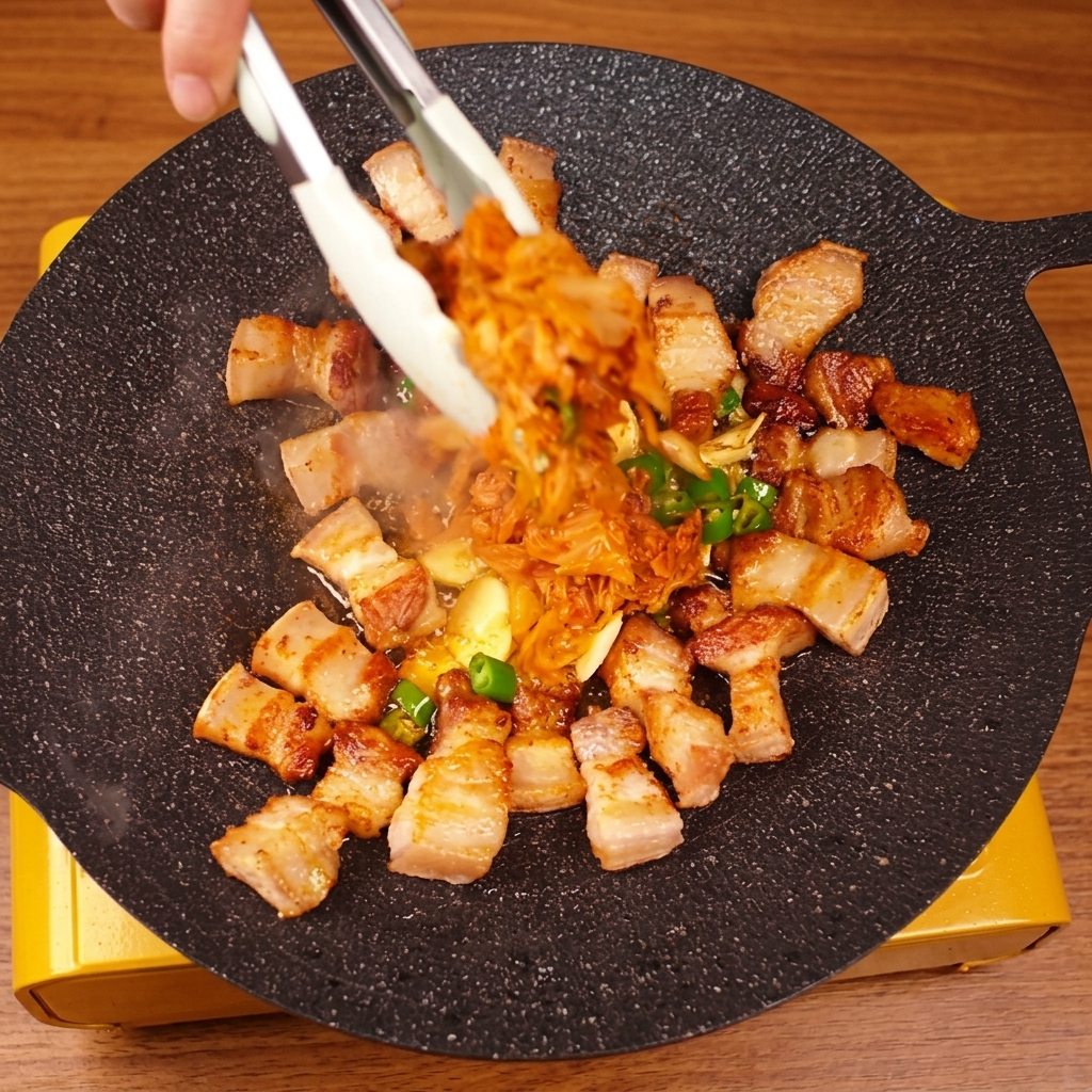 Mélange de poitrine de porc et de kimchi à laide dune pince.