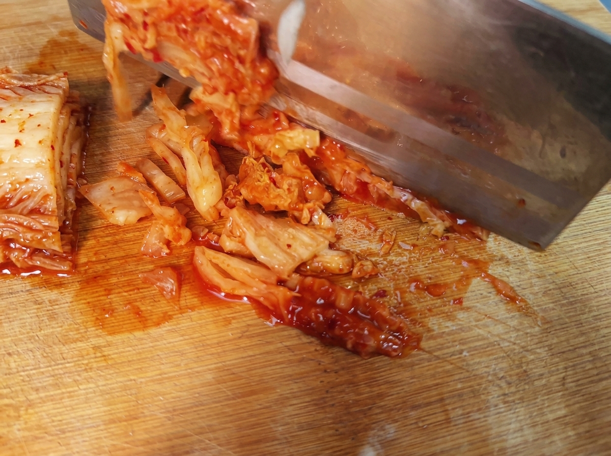 Tranches de kimchi coréen épicé disposées sur une planche à découper.