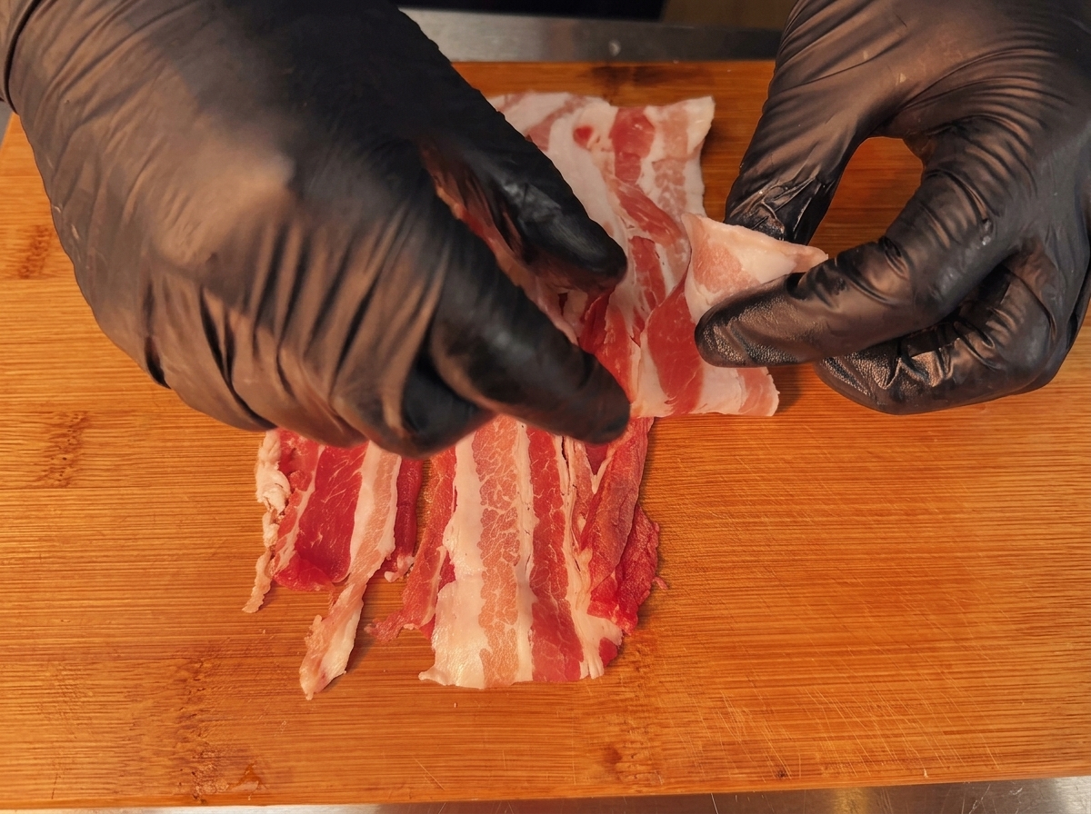 Tranches de poitrine de porc crue qui se chevauchent, préparées pour le processus de roulage.