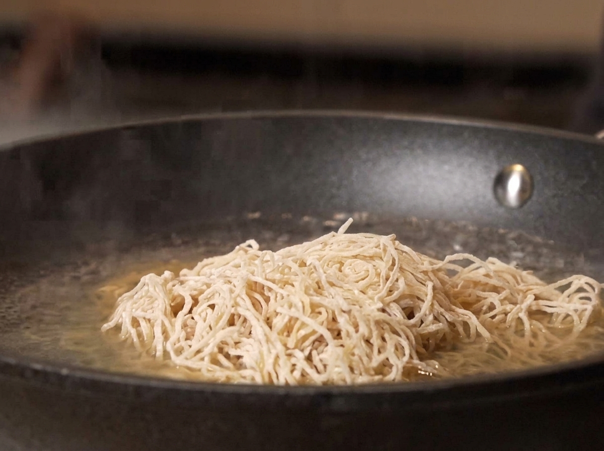 Nouilles crues plongées dans une casserole deau bouillante.