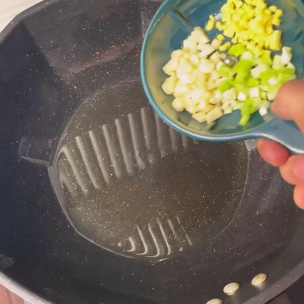 Oignons verts et ail hachés qui grésillent dans de lhuile chaude au wok.
