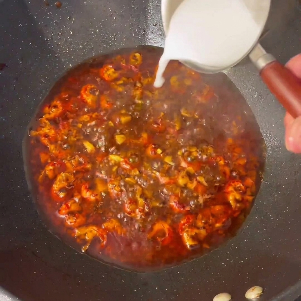 La fécule de maïs est versée dans la sauce bouillonante du wok.