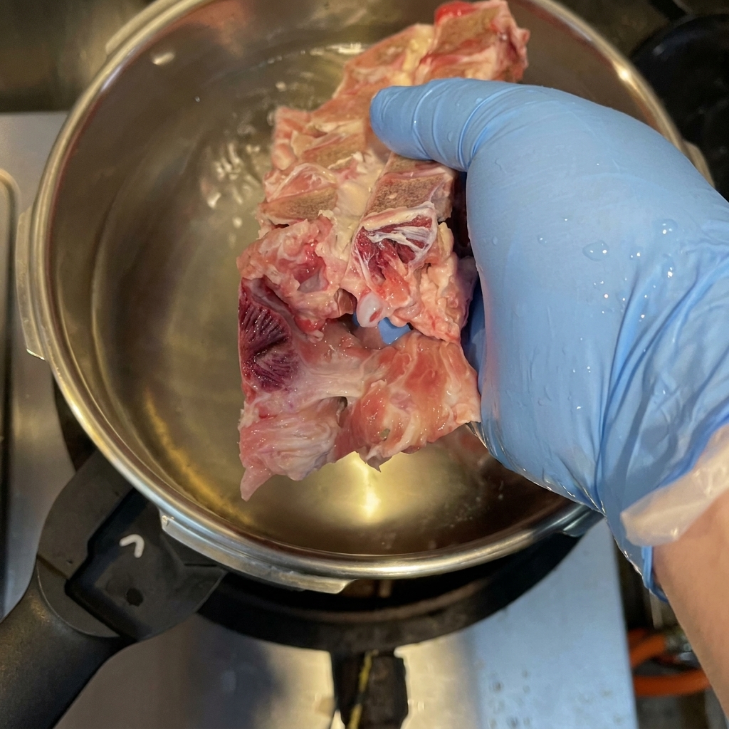 Os de porc, carcasse de poulet et pieds de porc bouillant dans une cocotte-minute pour éliminer les impuretés.