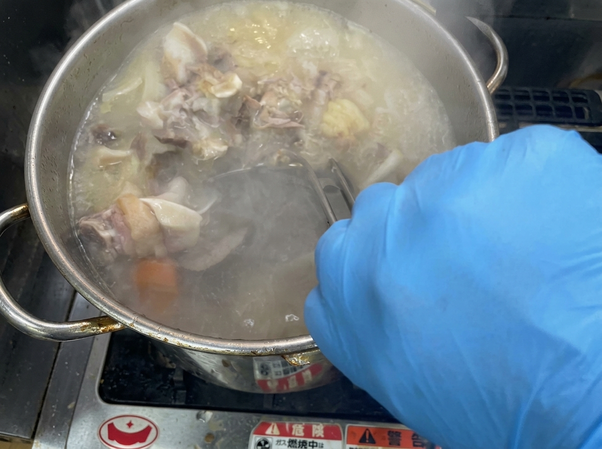 Mélange vigoureux dun bouillon crémeux dans une grande marmite en inox.