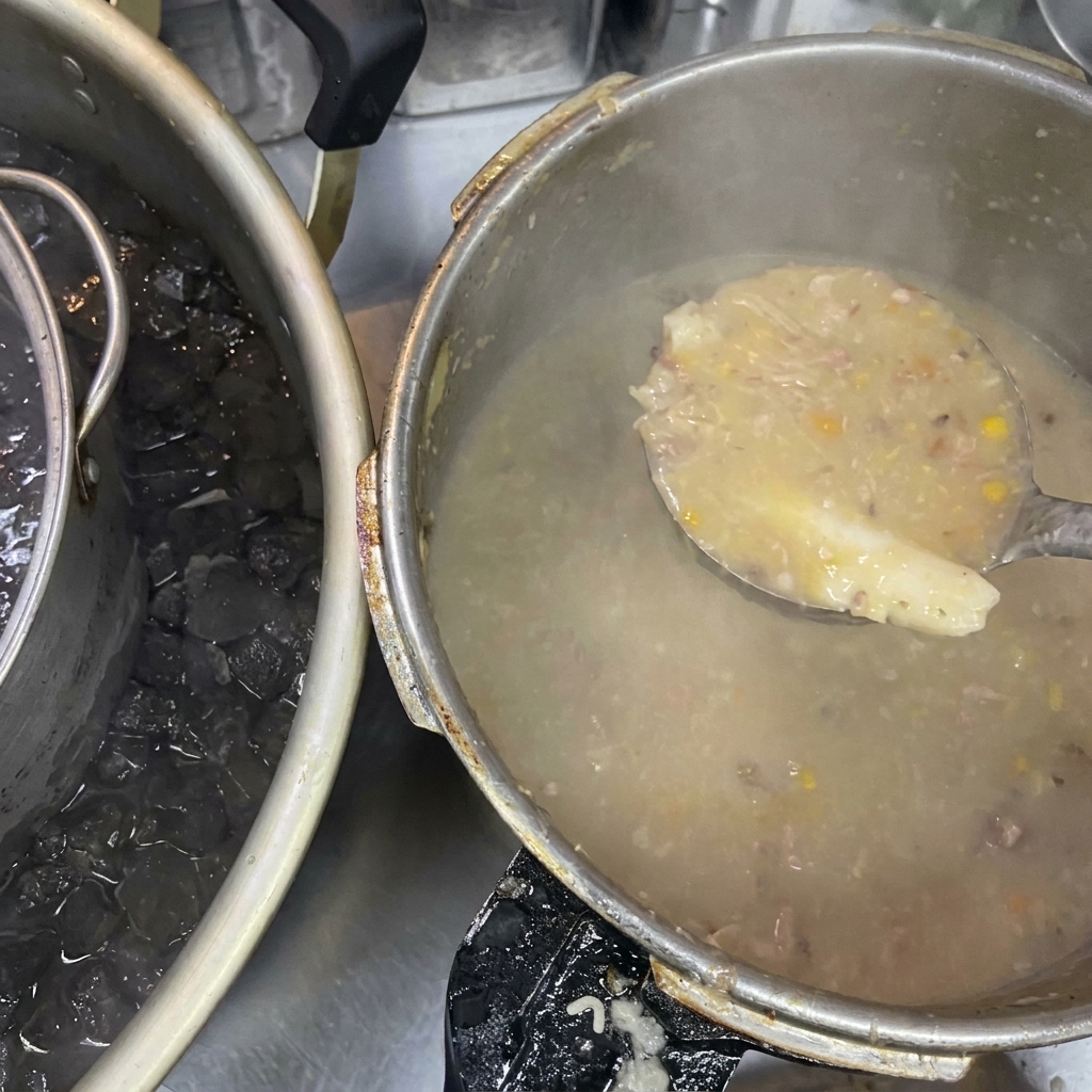 Une louche contenant un bouillon épais et trouble à côté dune grande marmite placée dans un bain de glace.