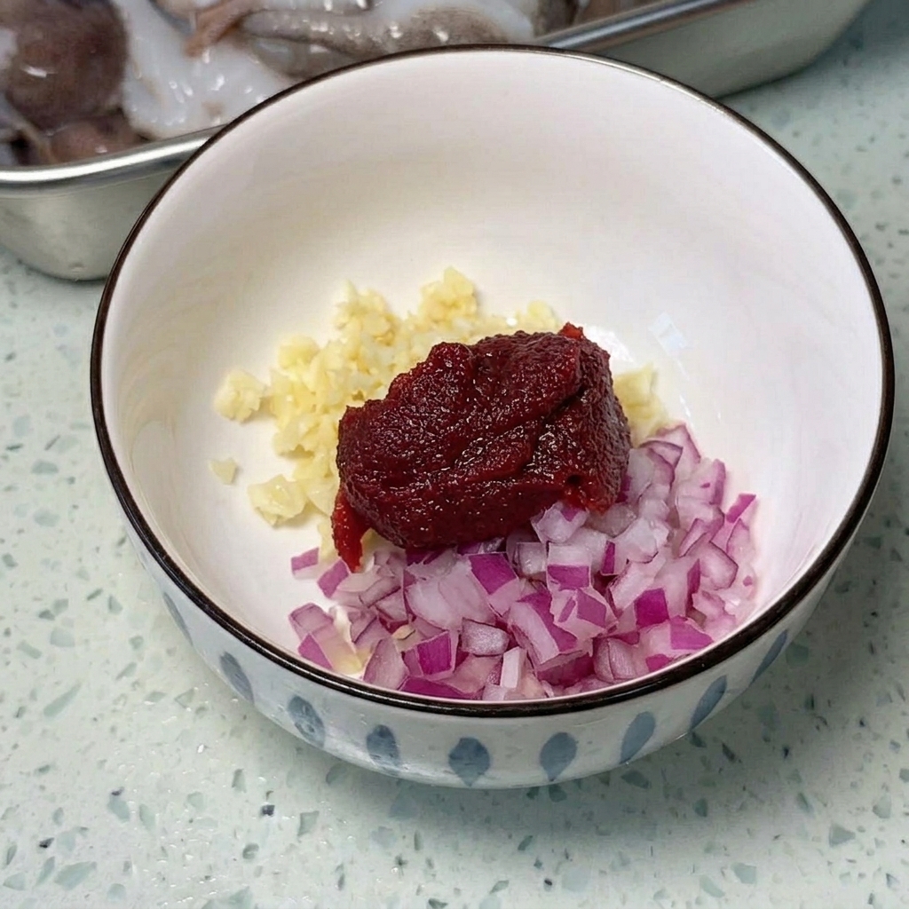 Une large poêle métallique garnie de tranches de spam, de saucisses et de cubes de tofu, prêts à être cuisinés.