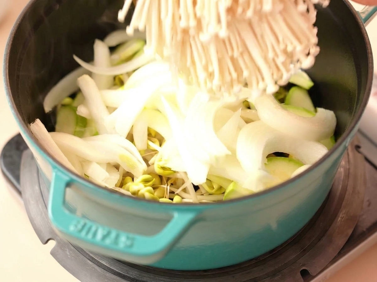 Champignons enoki, oignons et courgettes ajoutés sur les pousses de soja.