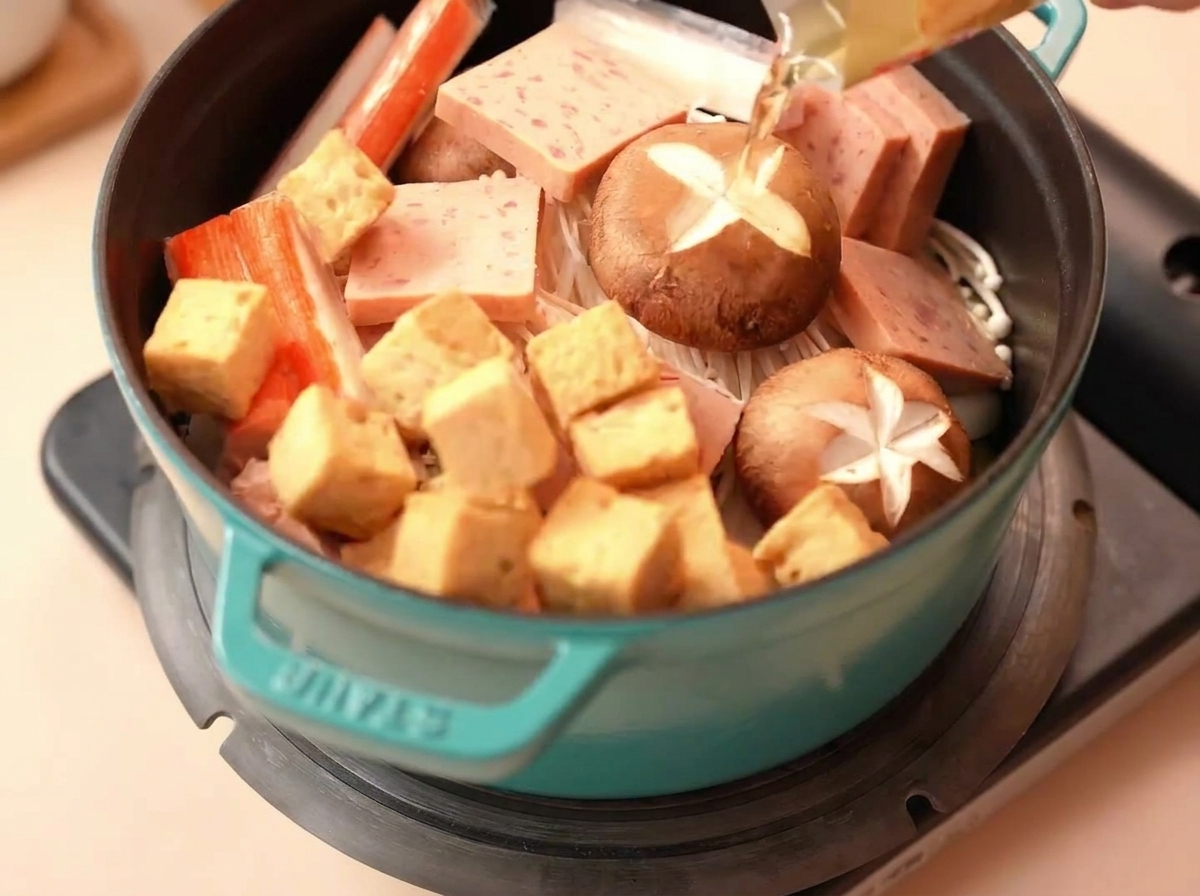 Tofu de poisson et bâtonnets de crabe placés soigneusement dans la marmite.