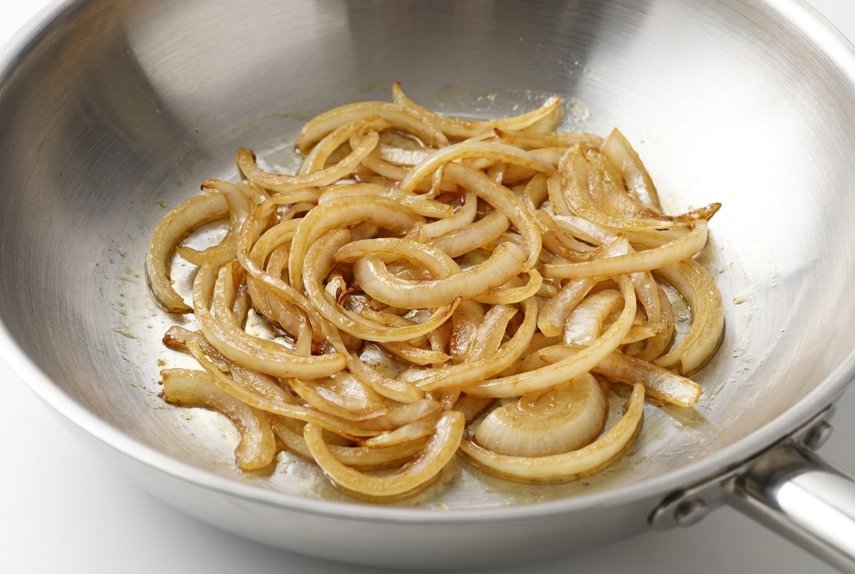 Poivre noir fraîchement moulu saupoudré sur les oignons sautés.