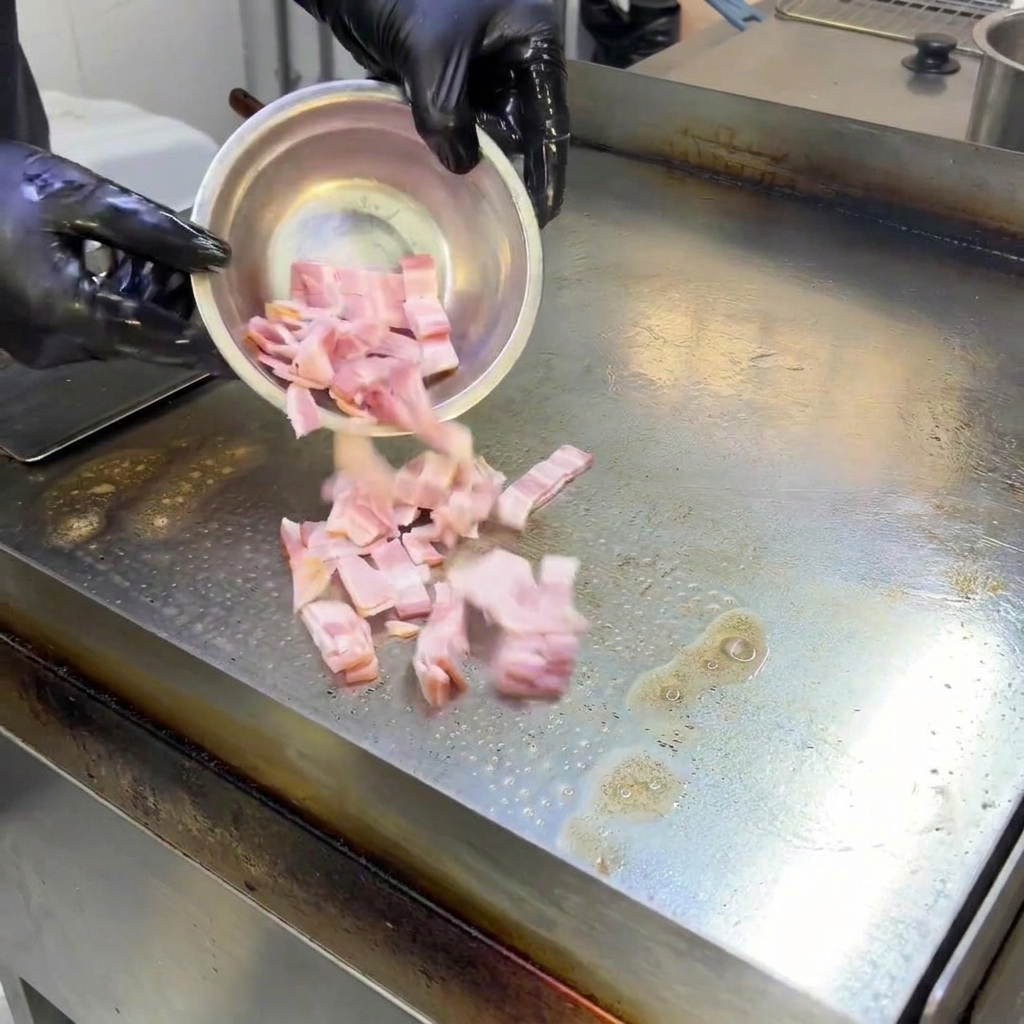 Morceaux de bacon qui grésillent sur une plaque de cuisson chaude, libérant leur graisse.