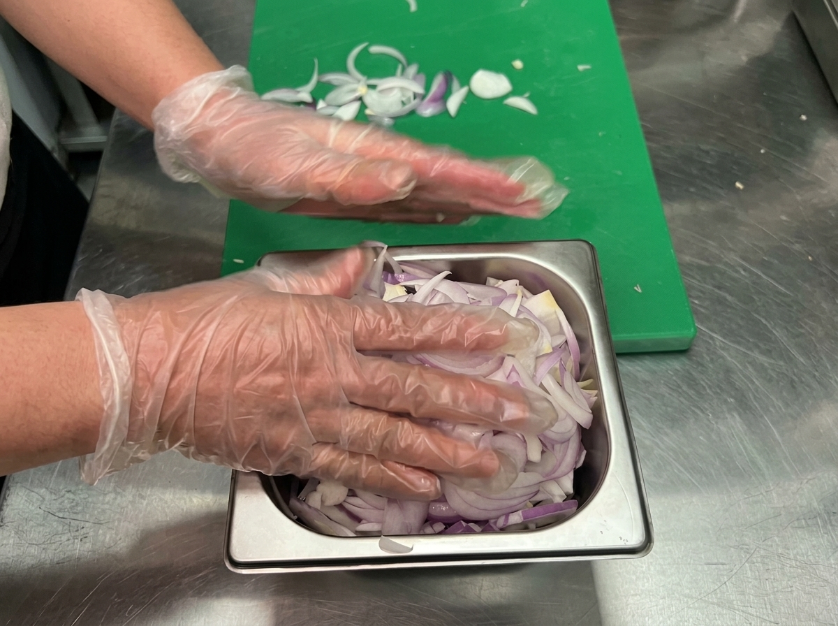 Oignons en train de sauter dans une poêle avec un filet de vin rouge et dhuile dolive mélangés.