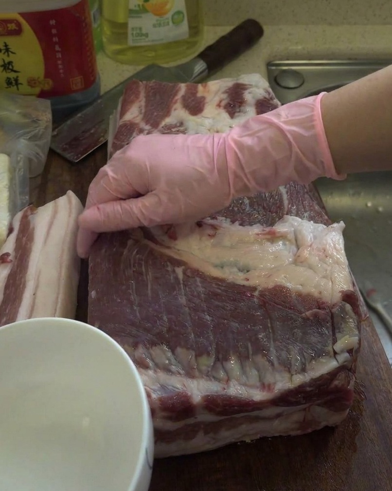 Un gros morceau de poitrine de porc crue frotté avec de lalcool blanc sur une planche à découper en bois.