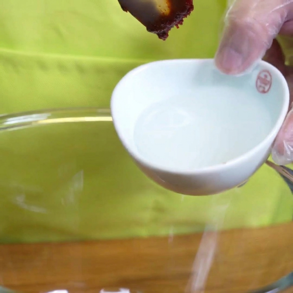 Sirop damidon épais versé à la cuillère dans un bol avec les ingrédients de la marinade.
