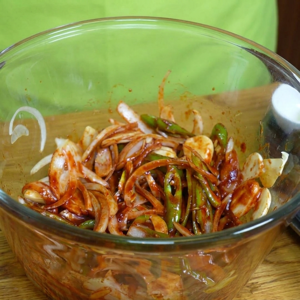 Fines tranches de poitrine de porc ajoutées dans un bol avec la marinade et les légumes.