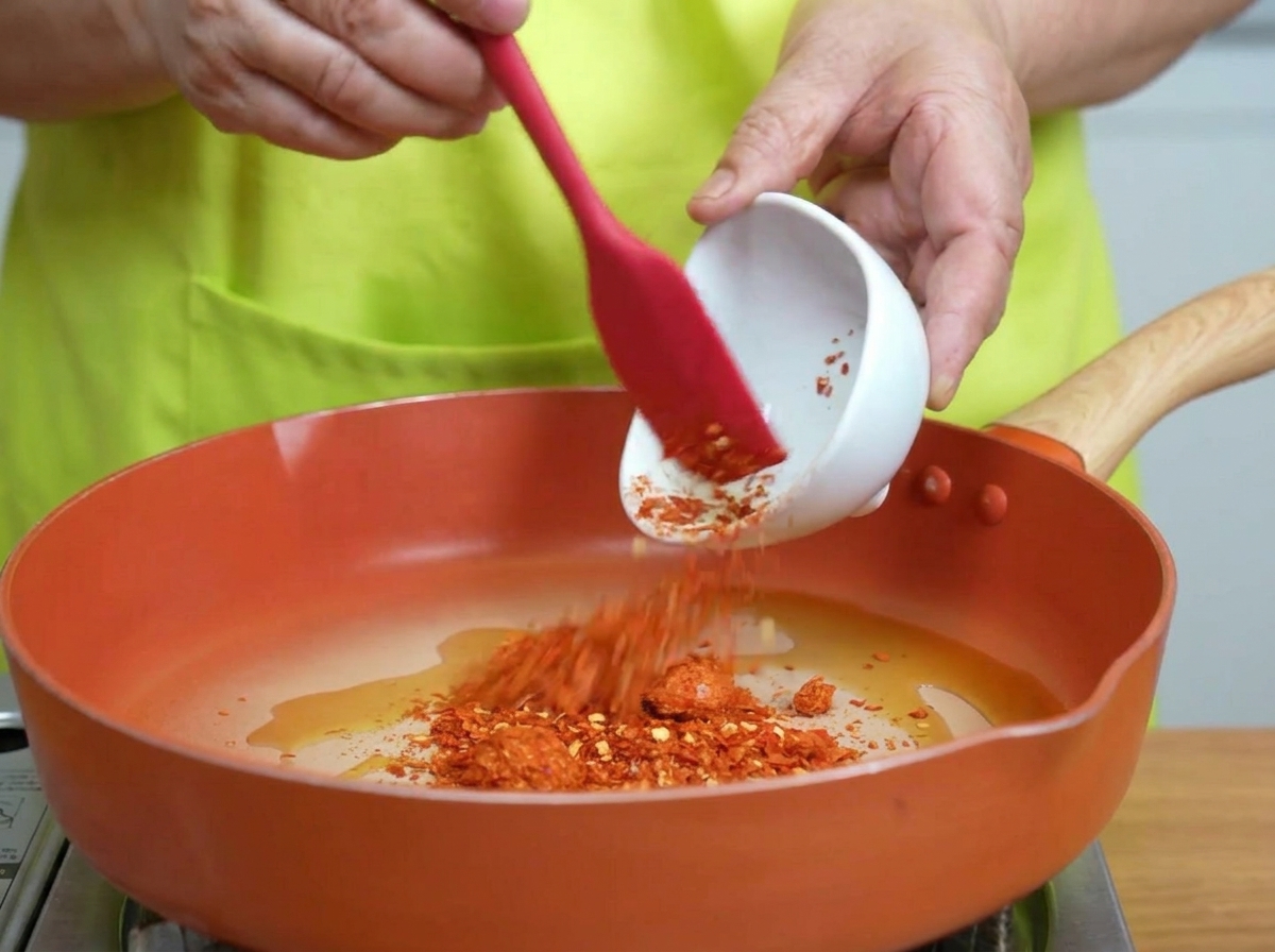 Flocons de piment remués dans de lhuile chaude frémissante dans une poêle.