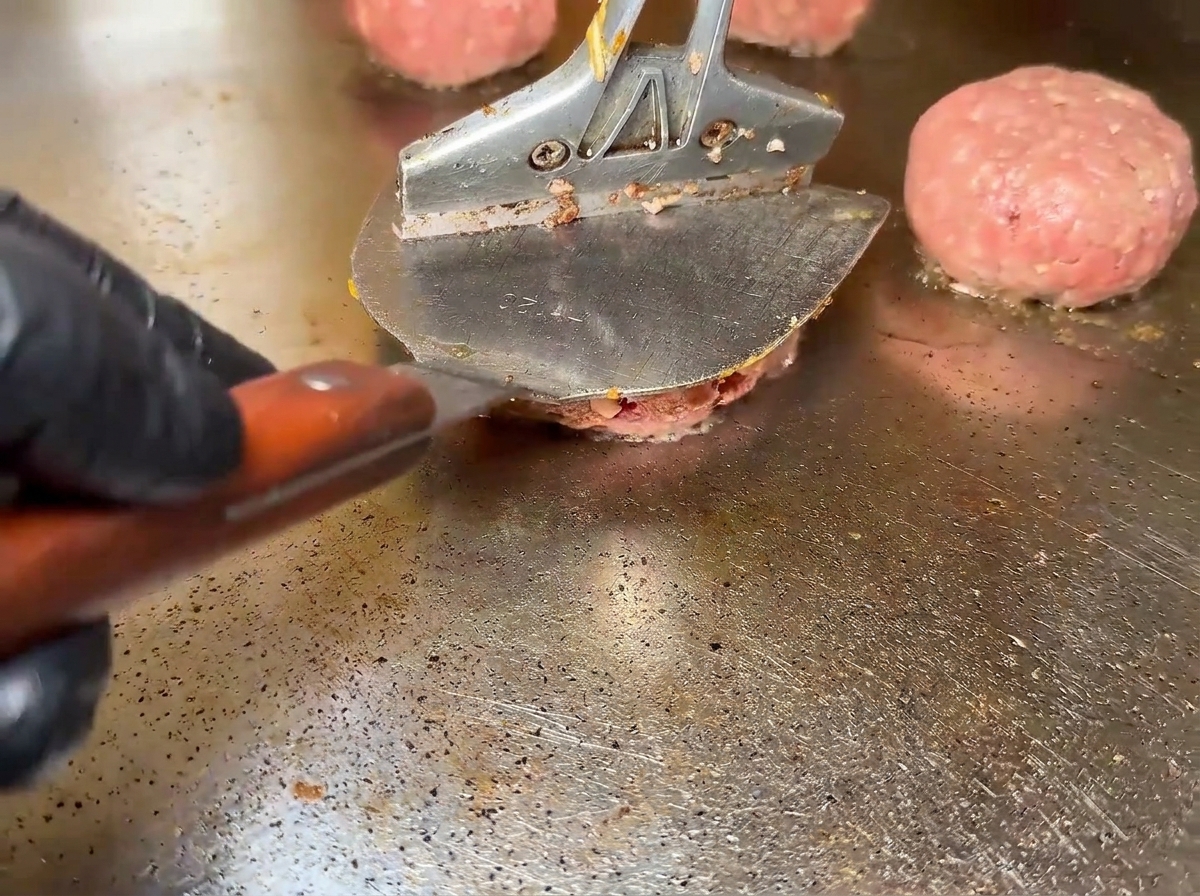Steaks de bœuf crus grésillant sur une plaque de cuisson brûlante.