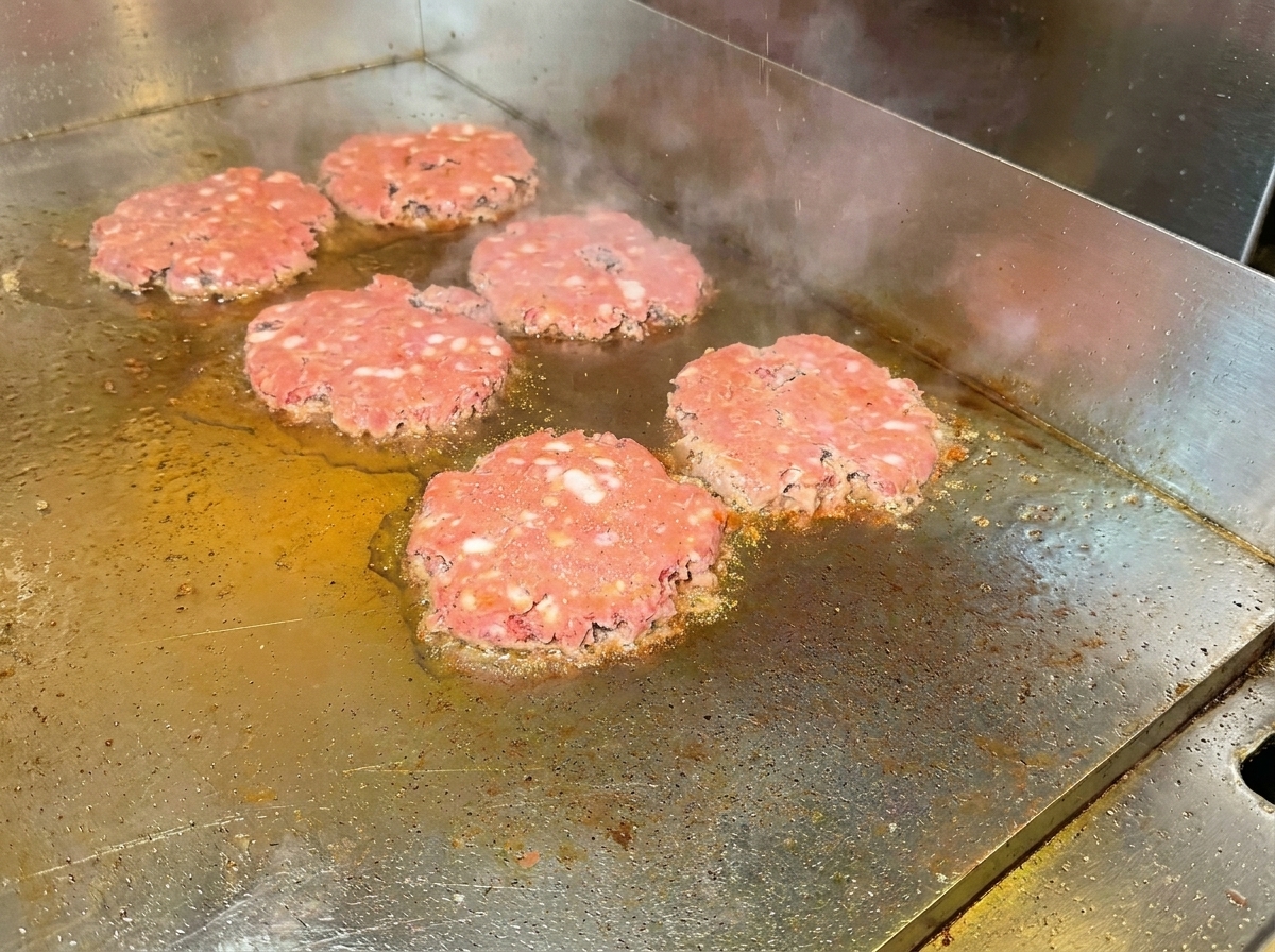 Steaks retournés sur la plaque, dévoilant une surface bien dorée et assaisonnée.