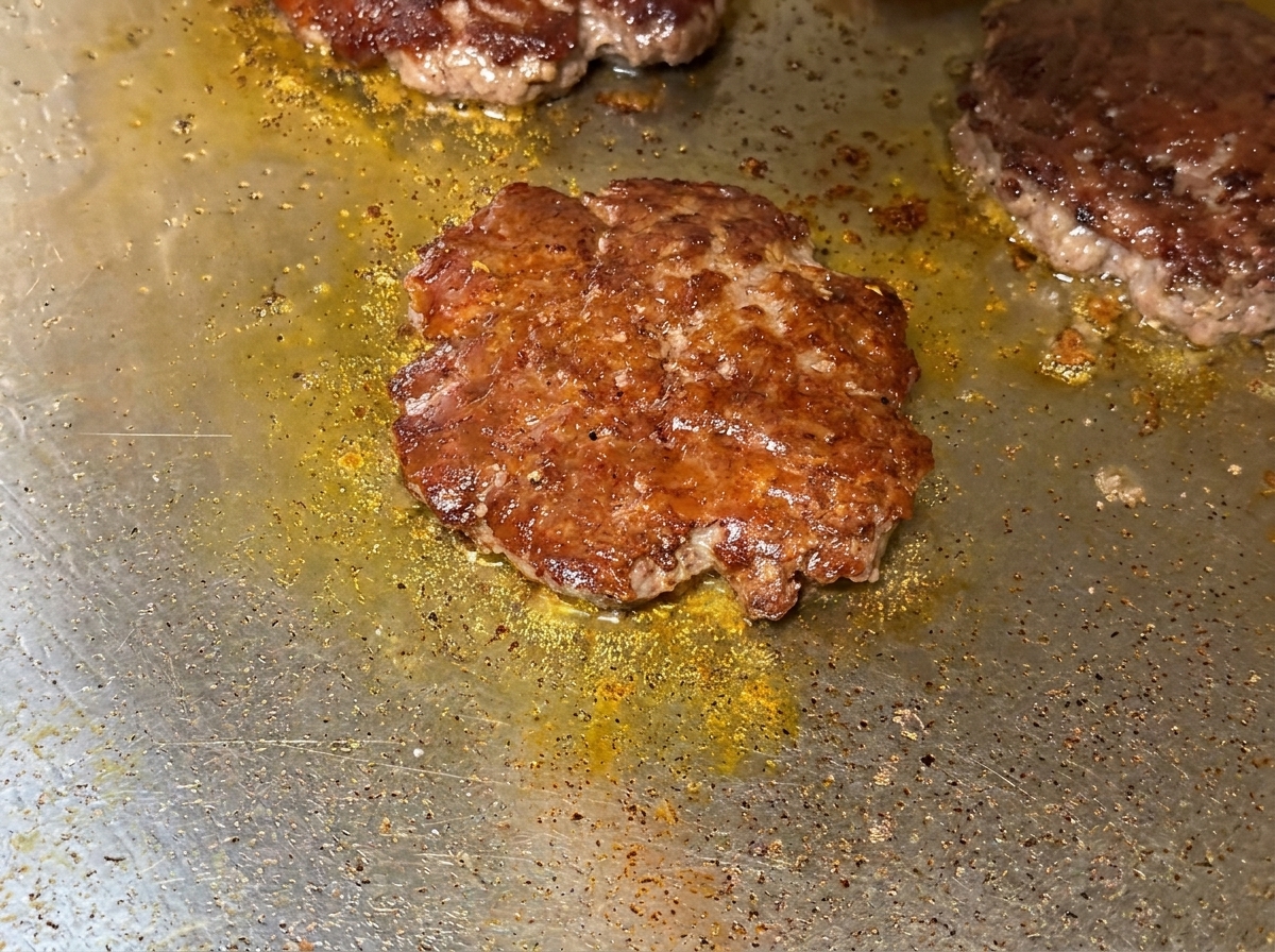 Gros plan sur du fromage fondu recouvrant les steaks bien chauds sur la plaque.