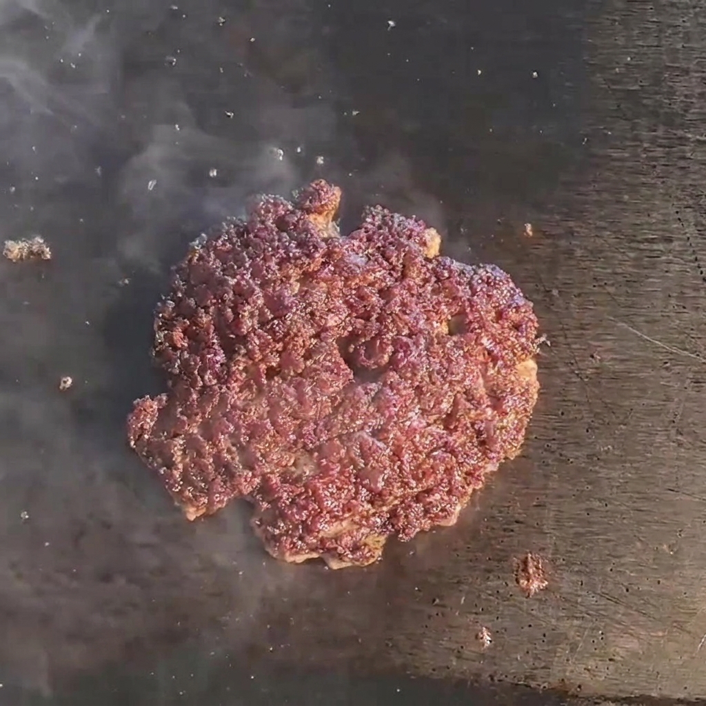 Une tranche de fromage fondant sur un steak de bœuf juteux et doré sur le gril.