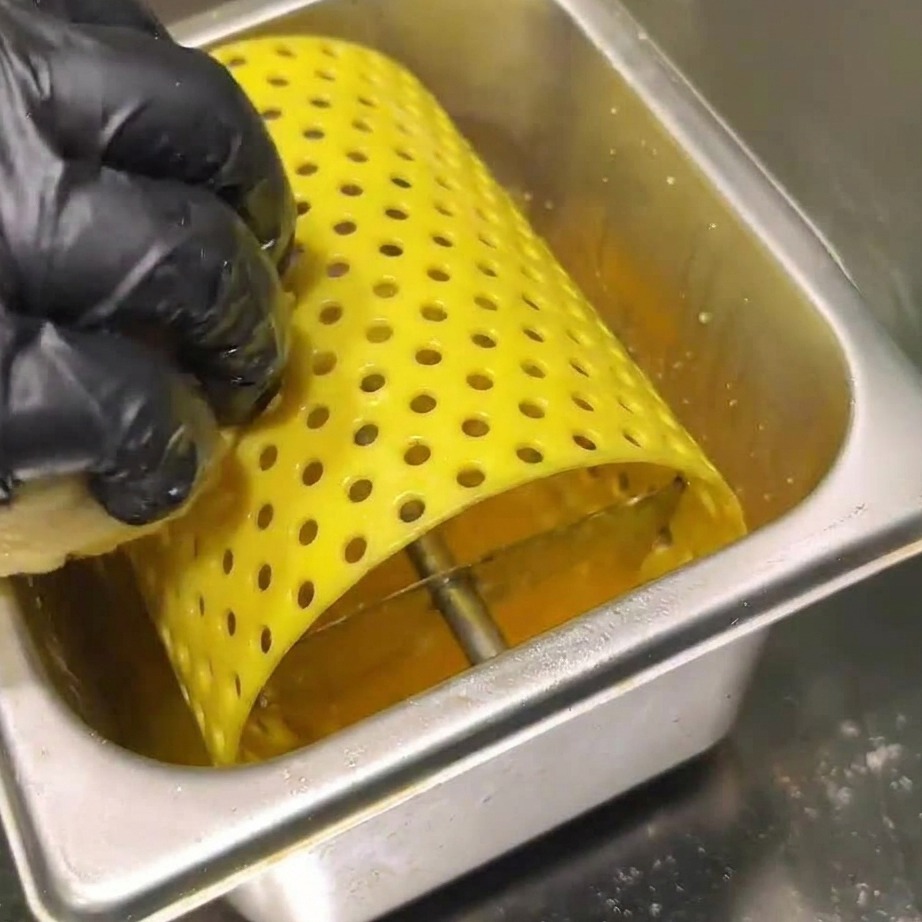Steaks hachés grésillant sur un grill chaud, pressés par une spatule métallique.