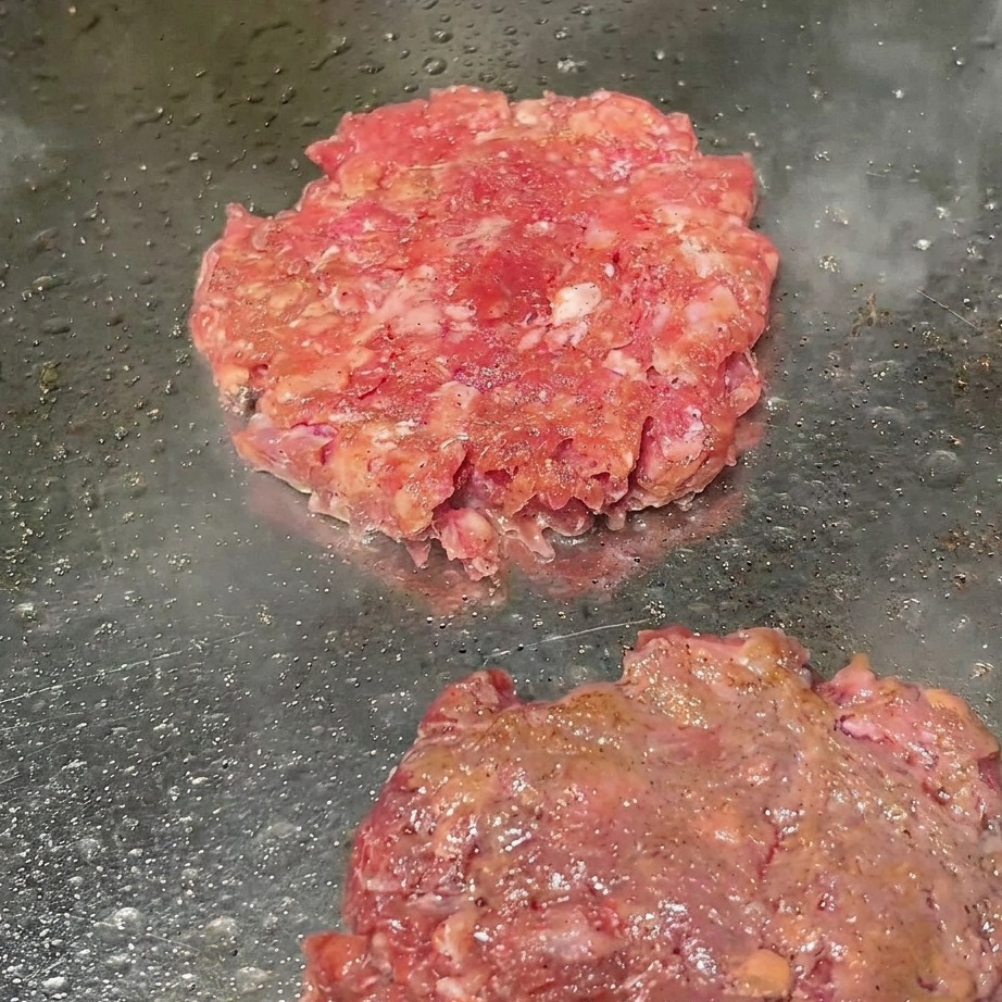 Steaks sur le grill saupoudrés de poivre noir fraîchement moulu.