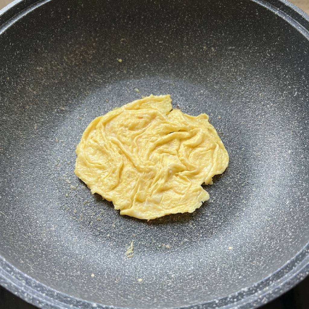 Une tranche de fromage fondant sur un œuf dans une poêle.