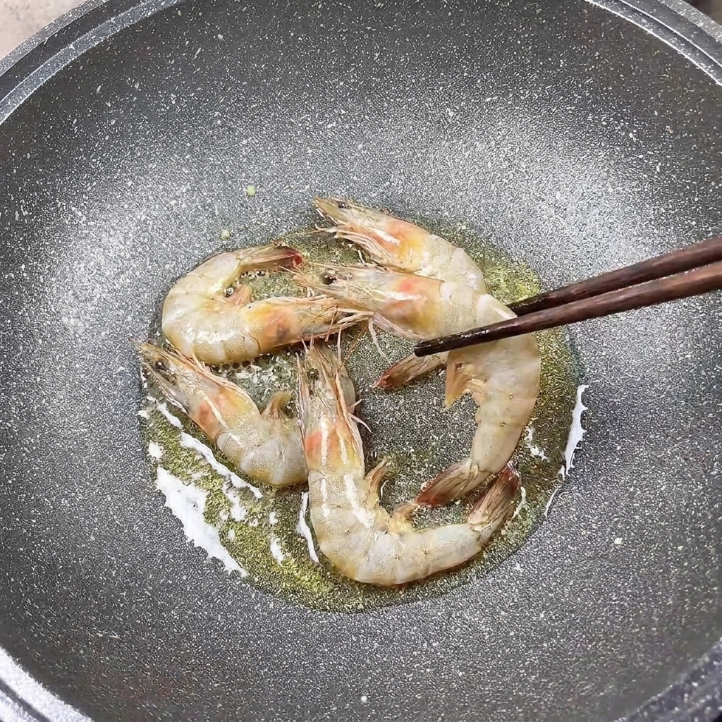 Crevettes assaisonnées saisies à la poêle avec des baguettes.