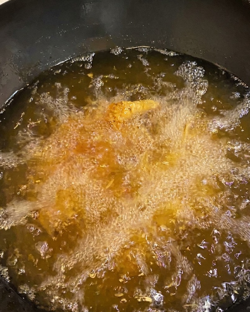Cuisses de poulet en friture, affichant une croûte dorée et brune.