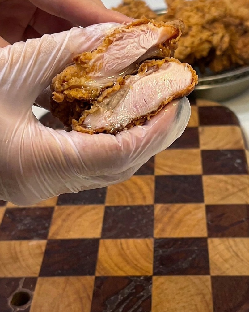 Gros plan sur un filet de poulet frit coupé en deux, montrant la viande blanche et juteuse à lintérieur.