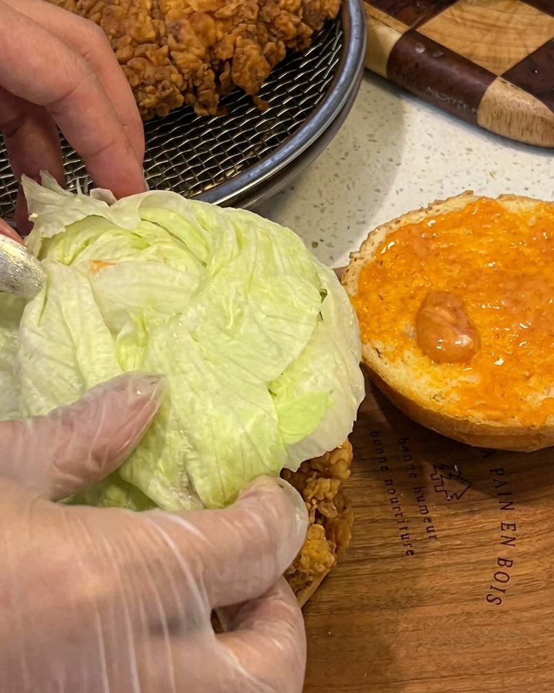 Assemblage dun burger de poulet avec un filet croustillant, laitue fraîche et sauce sur un pain grillé.