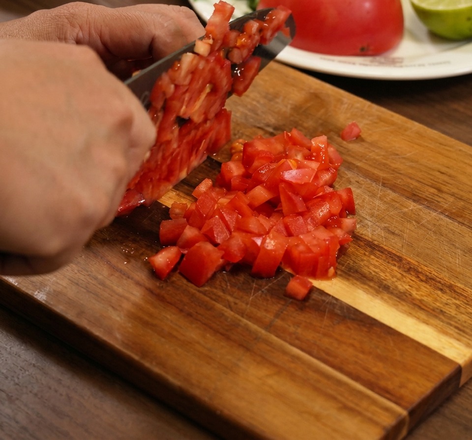 Gros plan sur des tomates, oignons rouges et coriandre mélangés dans un bol.