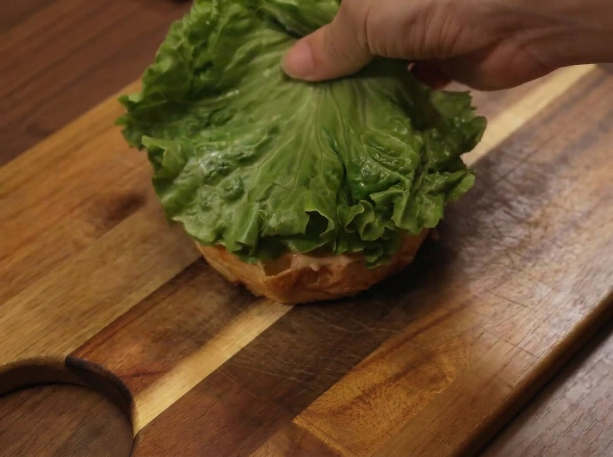 Ajout dune feuille de salade sur la base du burger pendant le montage.