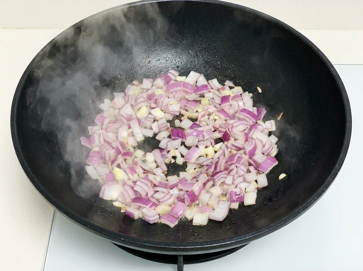 Oignons rouges hachés sautant dans un wok chaud avec de la vapeur.