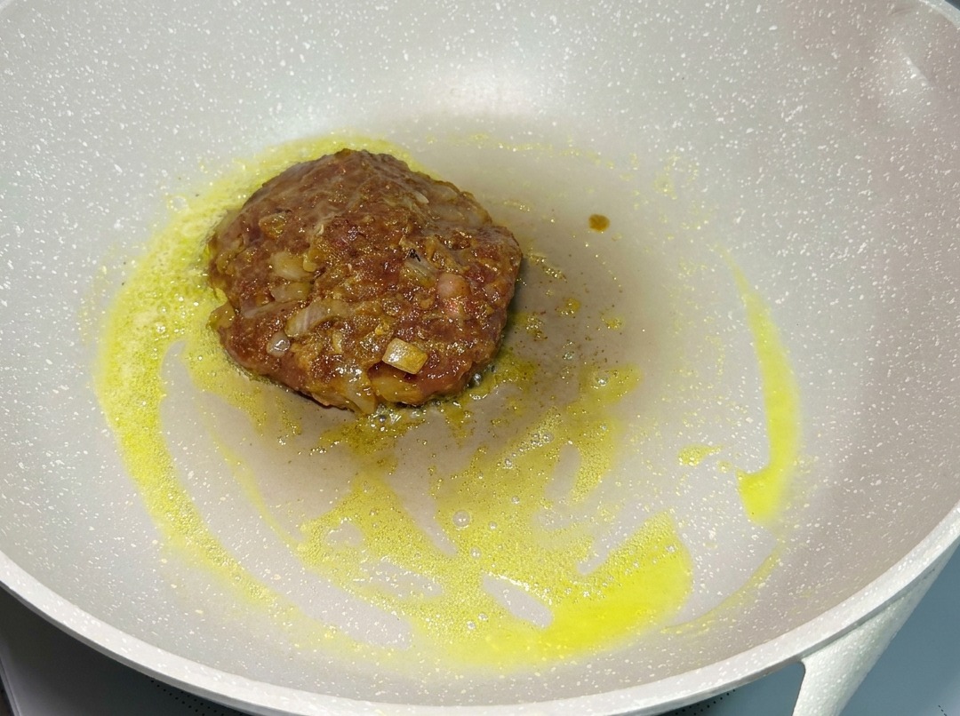 Un steak de bœuf assaisonné cuisant dans une poêle à feu doux.
