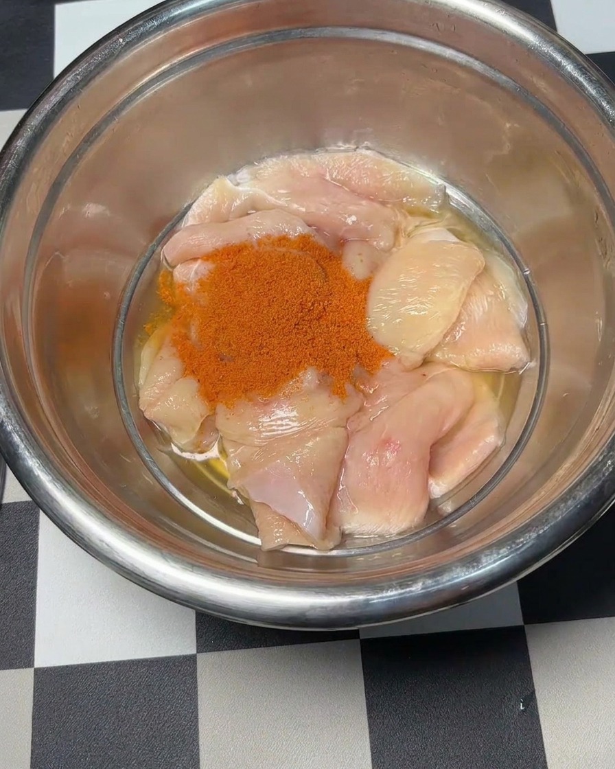 La poudre à marinade Orléans rouge versée sur les morceaux de poulet.