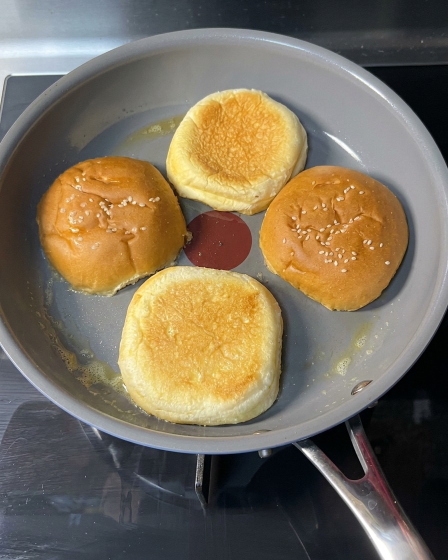 Une main retournant un pain toasté dans une poêle, montrant une surface dorée et croustillante.