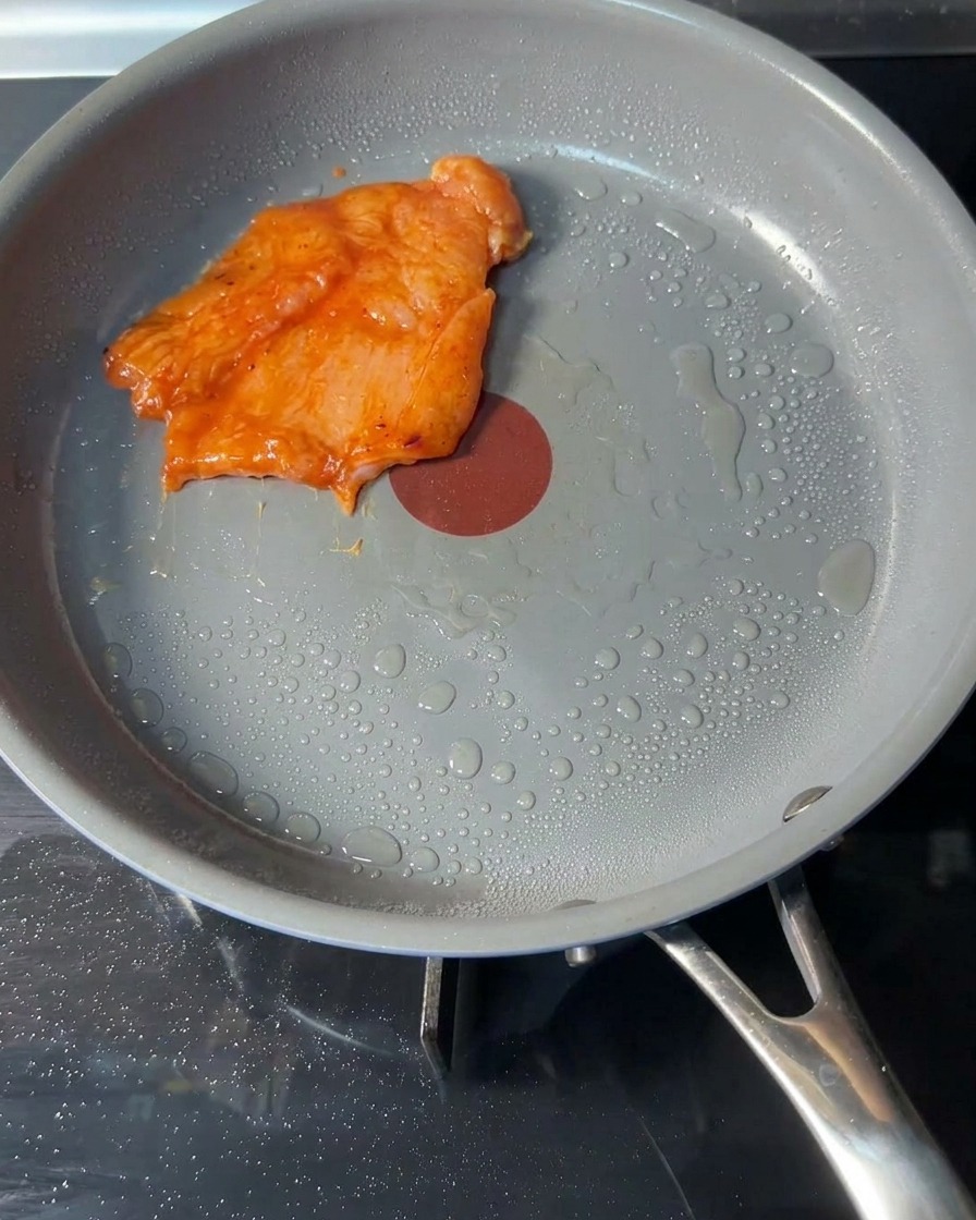 Steaks de poulet crus posés dans une poêle chaude avec un peu dhuile.
