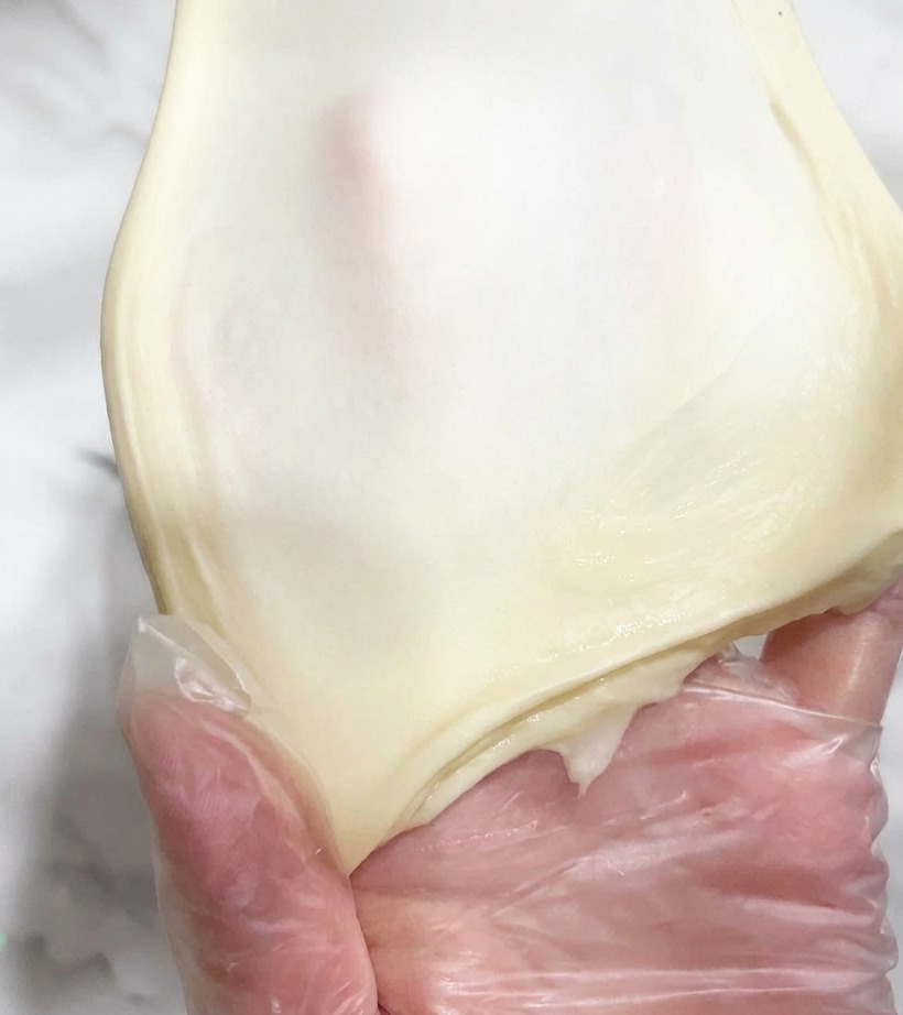Un morceau de pâte étiré à la main pour montrer sa transparence.