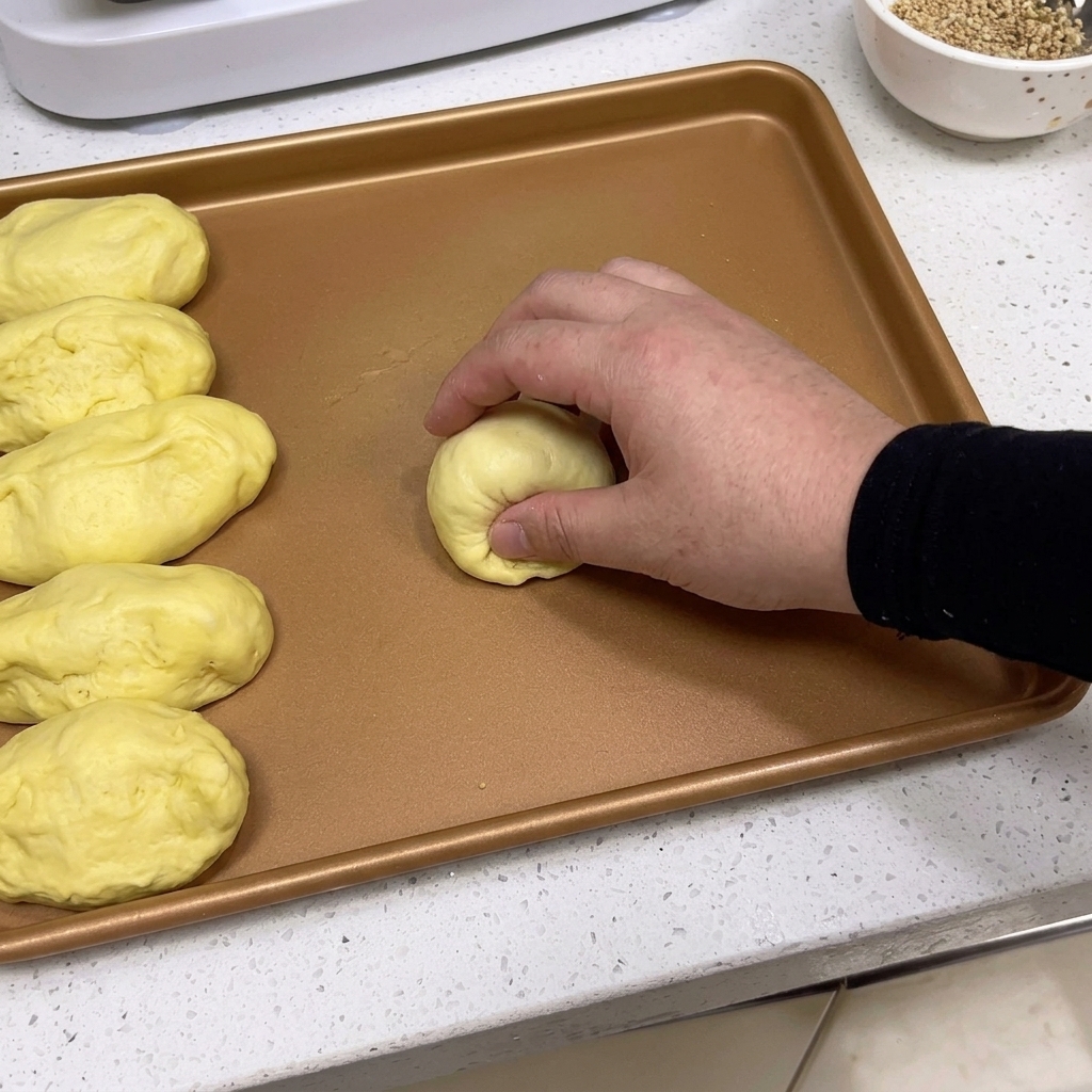 Mains façonnant un morceau de pâte en une boule lisse sur un plateau.