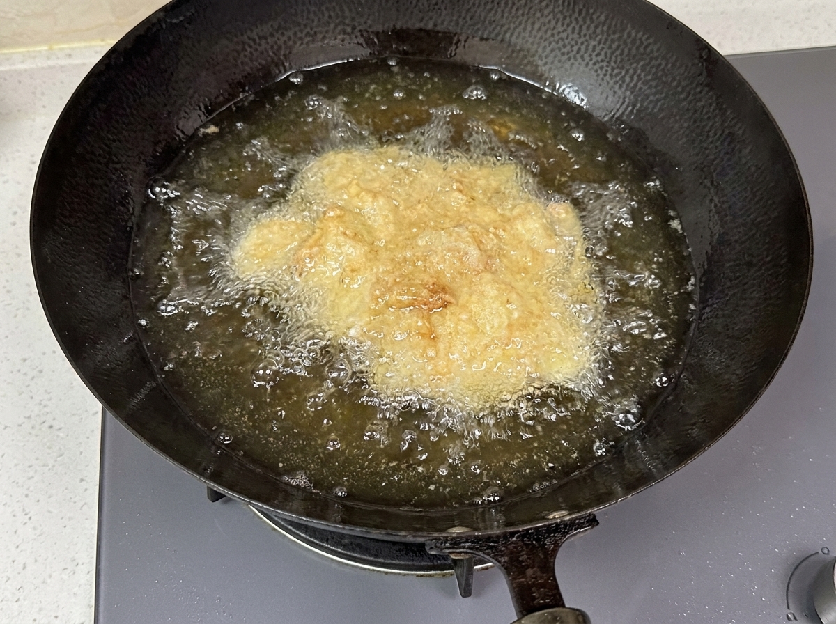 Morceaux de poulet panés bouillonnant dans lhuile chaude dun wok.